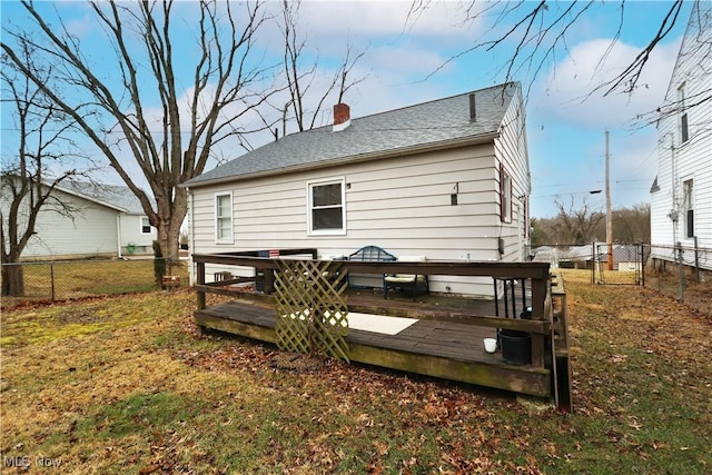 back of property with a fenced backyard, a chimney, a lawn, and a wooden deck
