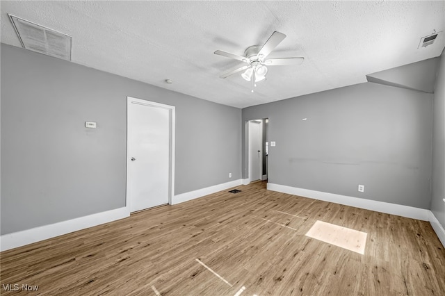 empty room featuring ceiling fan, a textured ceiling, wood finished floors, and visible vents