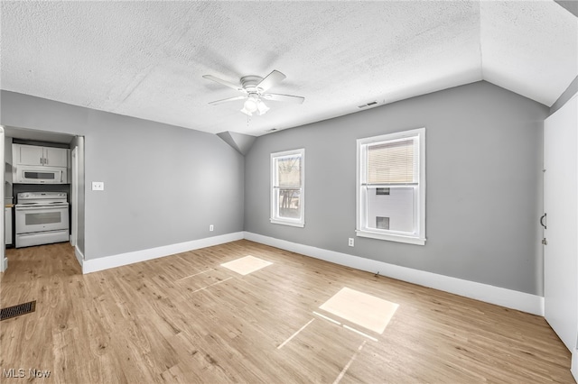 unfurnished room featuring light wood-style floors, visible vents, and vaulted ceiling