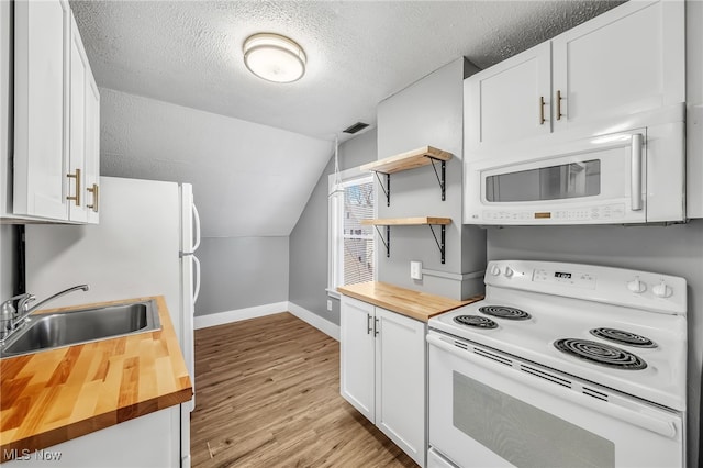 kitchen with wooden counters, light wood-style floors, a sink, a textured ceiling, and white appliances