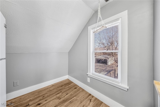 bonus room featuring vaulted ceiling, a textured ceiling, baseboards, and wood finished floors