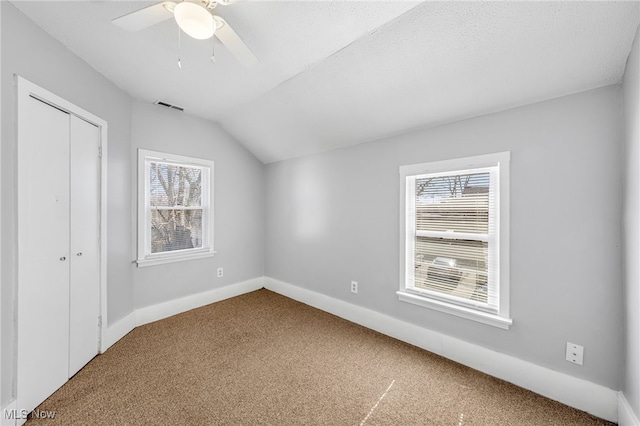 unfurnished bedroom with carpet floors, visible vents, a closet, and lofted ceiling