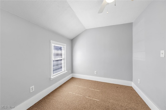 spare room with a textured ceiling, a ceiling fan, baseboards, vaulted ceiling, and carpet