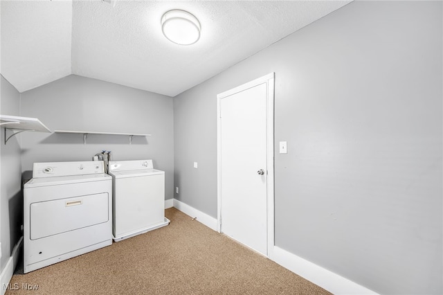 clothes washing area featuring light carpet, laundry area, baseboards, a textured ceiling, and washing machine and dryer