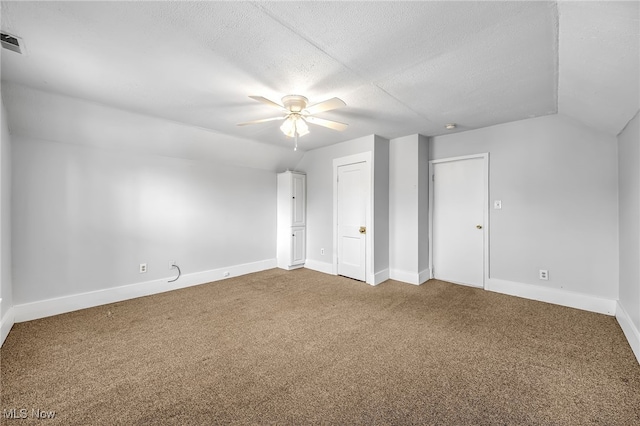 interior space with a textured ceiling, baseboards, vaulted ceiling, and carpet flooring