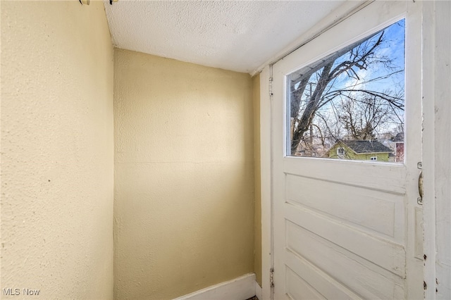 doorway with a textured ceiling and a textured wall