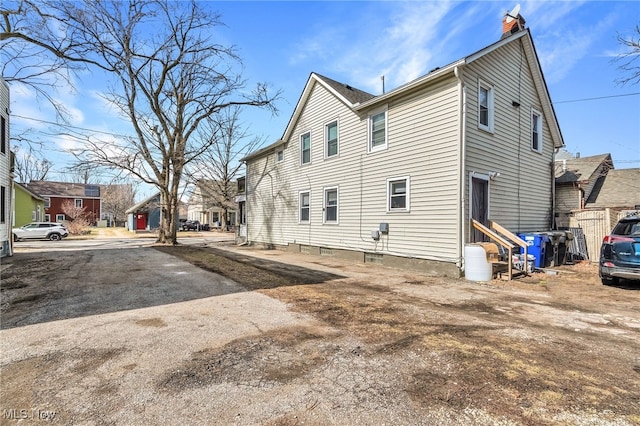 view of property exterior featuring entry steps, a chimney, and a residential view