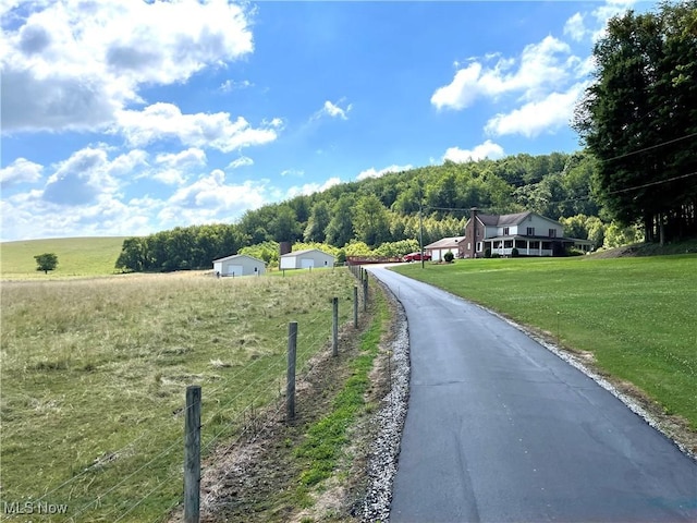 view of road featuring aphalt driveway, a rural view, and a wooded view