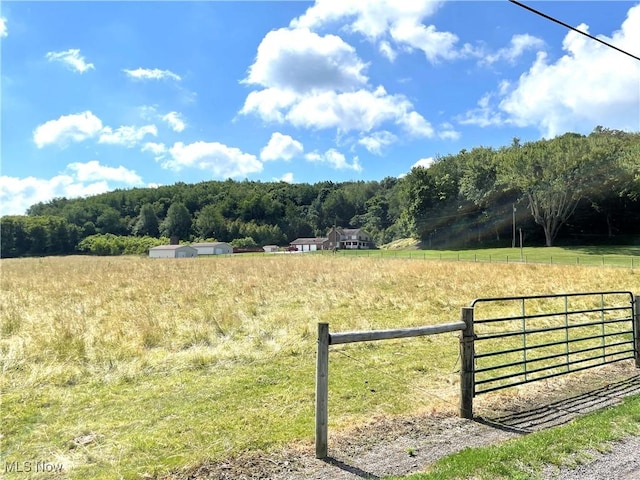 exterior space with a rural view, fence, and a forest view