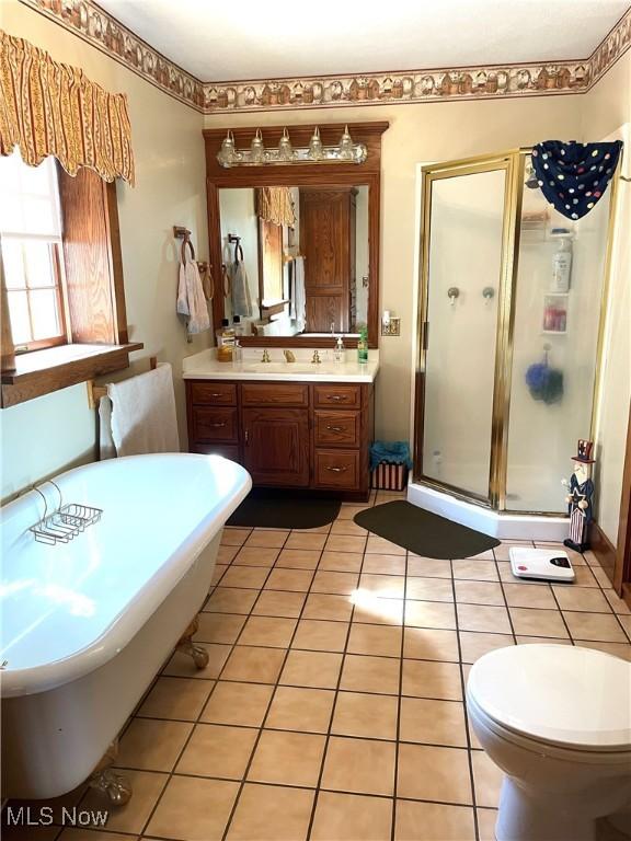 bathroom with a stall shower, a freestanding tub, tile patterned flooring, and vanity