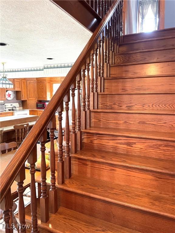 staircase featuring a textured ceiling