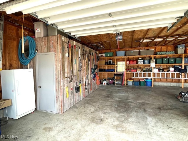 garage with a garage door opener and freestanding refrigerator