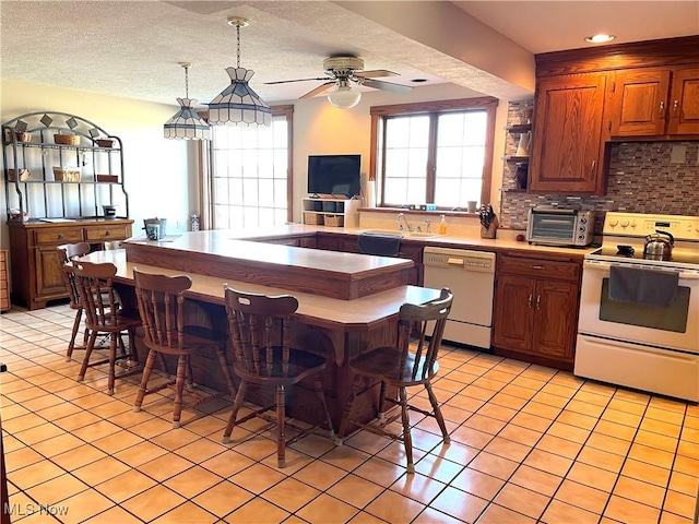 kitchen featuring light tile patterned flooring, white appliances, a sink, light countertops, and tasteful backsplash