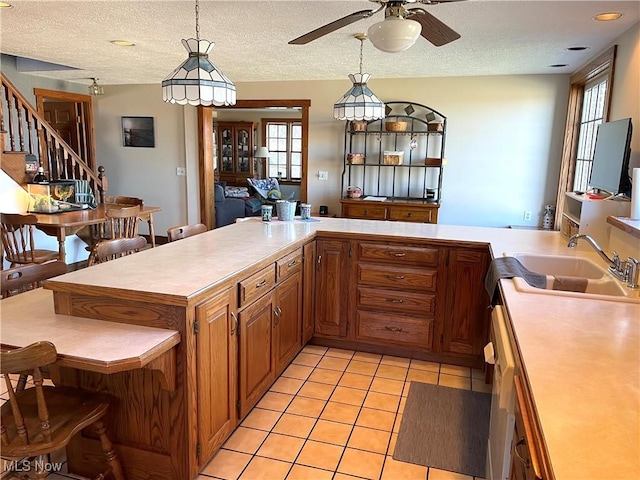 kitchen featuring light tile patterned floors, light countertops, a sink, and decorative light fixtures