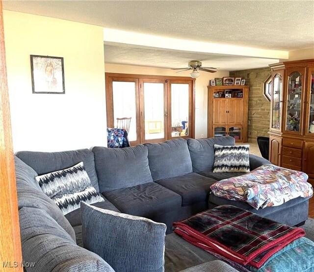 carpeted living area with ceiling fan and a textured ceiling