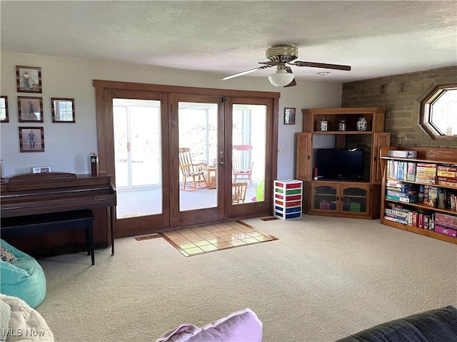 living room featuring carpet floors, ceiling fan, visible vents, and a textured ceiling