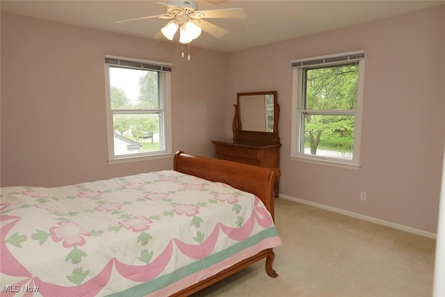 bedroom with light carpet, a ceiling fan, and baseboards