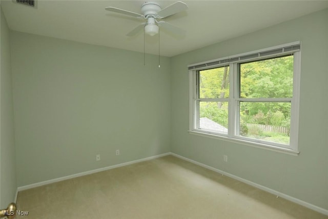 unfurnished room with a ceiling fan, light colored carpet, visible vents, and baseboards