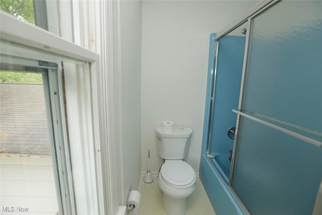 bathroom featuring combined bath / shower with glass door and toilet