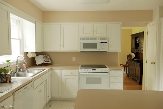 kitchen with white appliances, light countertops, a sink, and white cabinets