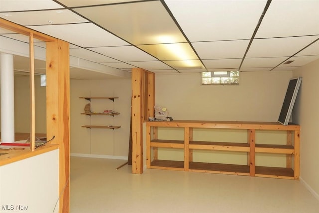 finished basement featuring baseboards and a drop ceiling