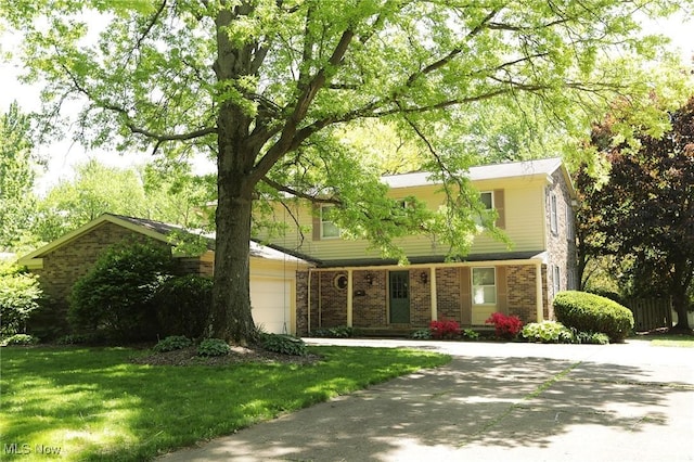 colonial inspired home with a garage, concrete driveway, brick siding, and a front lawn