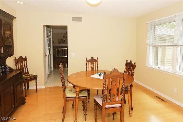 dining space with baseboards, visible vents, and light wood finished floors