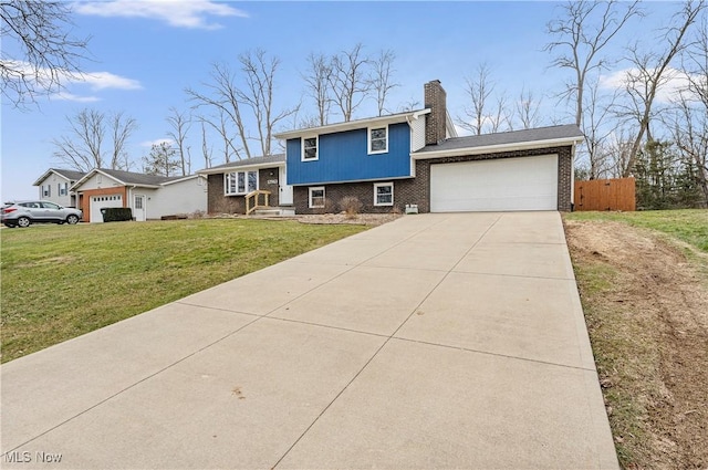 tri-level home featuring an attached garage, a chimney, a front lawn, and brick siding