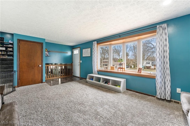 unfurnished room with carpet, a textured ceiling, and baseboards