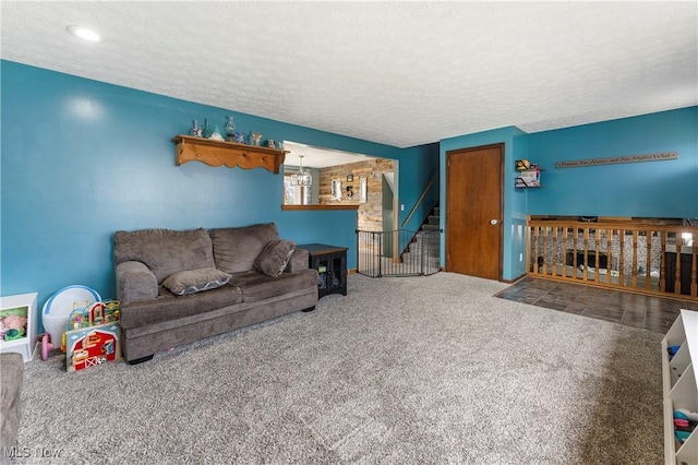 living area with a textured ceiling, stairs, and carpet flooring