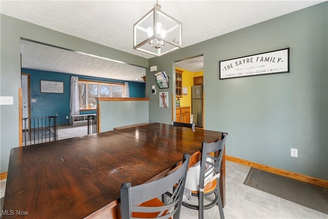 dining area with a chandelier, a textured ceiling, and baseboards