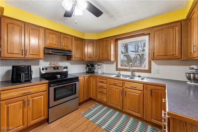 kitchen featuring brown cabinetry, light wood-style flooring, stainless steel range with electric cooktop, under cabinet range hood, and a sink