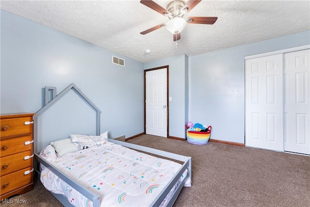 bedroom with a textured ceiling, carpet floors, visible vents, baseboards, and a closet