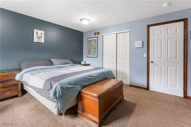 bedroom with baseboards, visible vents, light colored carpet, a textured ceiling, and a closet