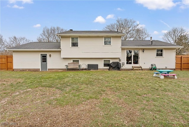 rear view of house with fence, central AC unit, and a lawn