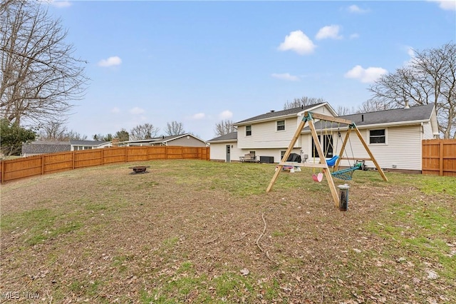 rear view of house with an outdoor fire pit, a fenced backyard, and a yard