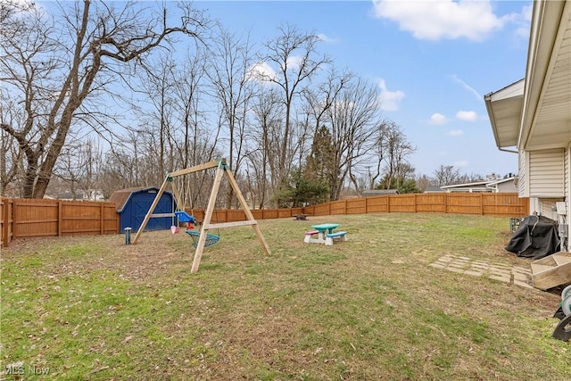 view of yard with a storage shed, an outdoor structure, a fenced backyard, and a playground