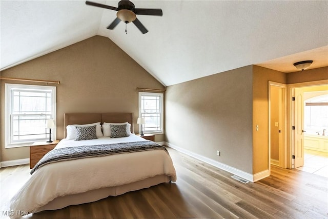 bedroom featuring wood finished floors, a ceiling fan, visible vents, vaulted ceiling, and baseboards