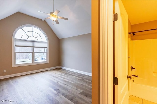 interior space featuring lofted ceiling, baseboards, a ceiling fan, and wood finished floors