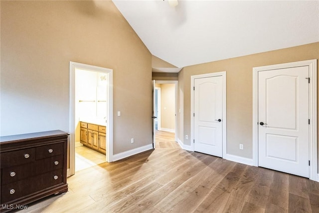 unfurnished bedroom featuring high vaulted ceiling, light wood-type flooring, connected bathroom, and baseboards