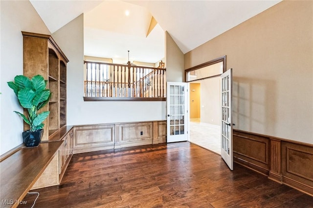 unfurnished room with wainscoting, high vaulted ceiling, wood finished floors, and french doors