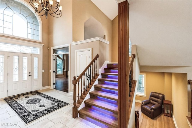 entryway featuring a chandelier, a towering ceiling, baseboards, and stairs