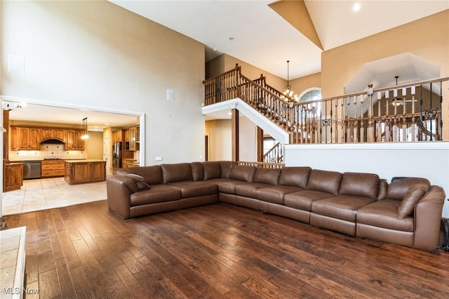 living area with light wood-style floors, stairway, a towering ceiling, and an inviting chandelier