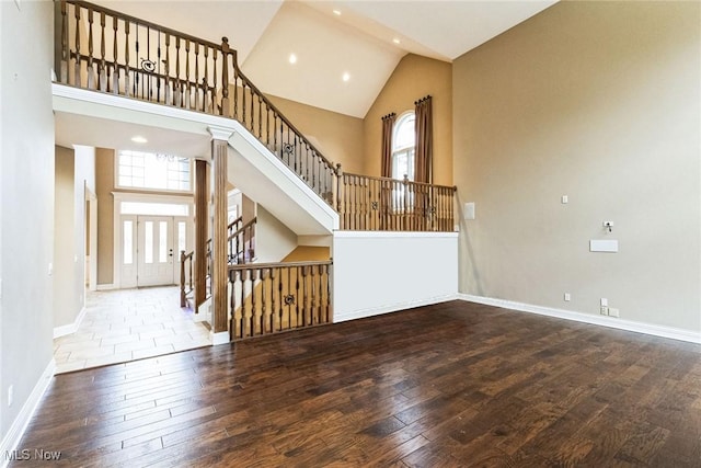 interior space with hardwood / wood-style flooring, baseboards, and high vaulted ceiling