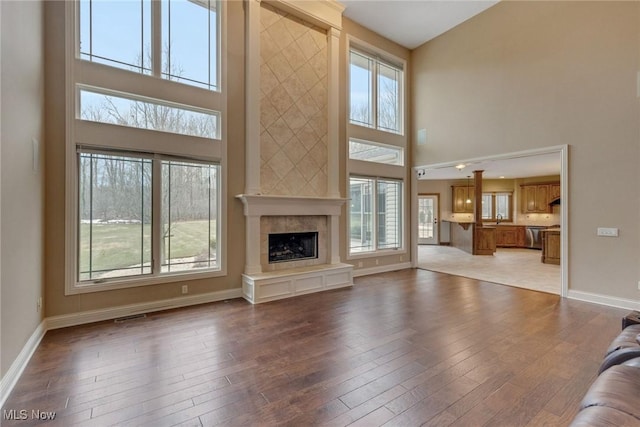 unfurnished living room featuring plenty of natural light, baseboards, wood finished floors, and a tile fireplace