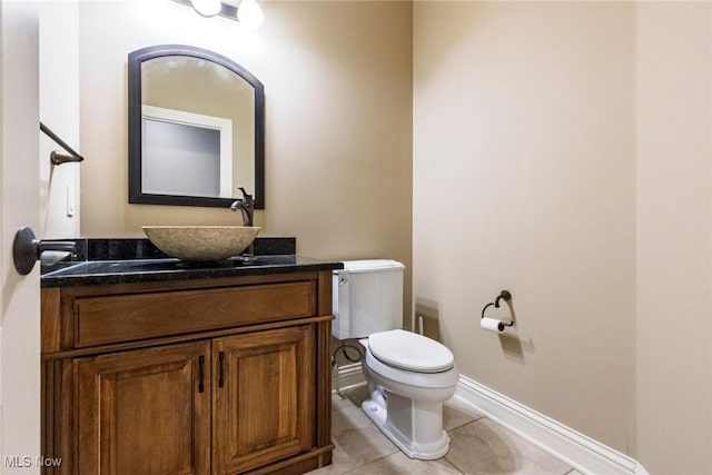 half bath featuring toilet, tile patterned flooring, baseboards, and vanity