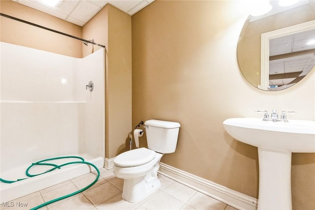 bathroom with a stall shower, a drop ceiling, tile patterned flooring, and toilet