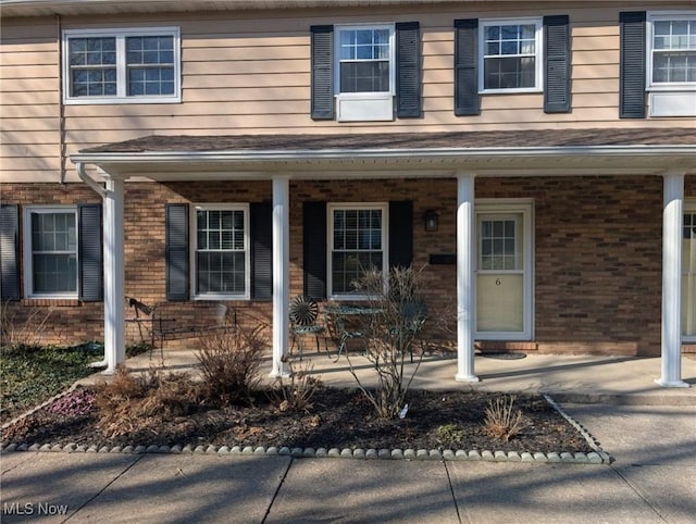 view of front of home with brick siding and covered porch