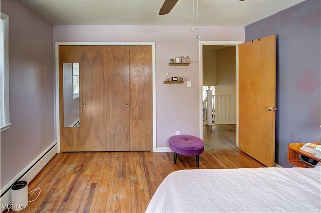 bedroom featuring ceiling fan, baseboard heating, a closet, and hardwood / wood-style flooring