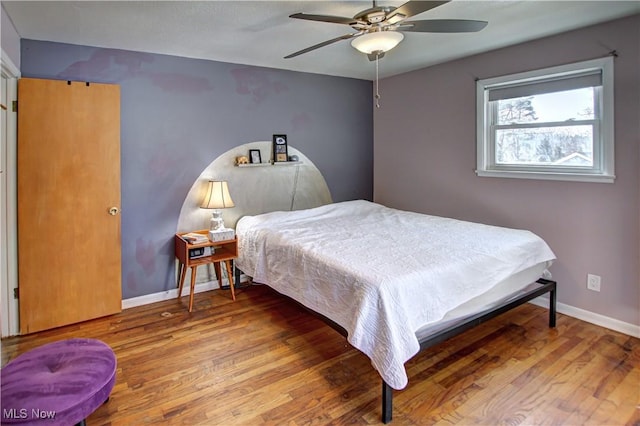 bedroom featuring ceiling fan, baseboards, and wood finished floors